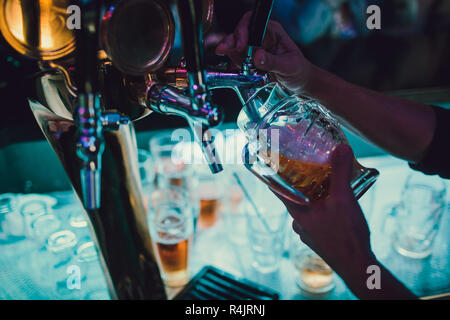 Barista versando da toccare birra fresca nel vetro nel pub. Foto Stock