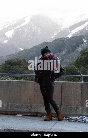 Giovane donna in posa di fronte della coperta di neve Mount Kosciuszko a Thredbo Foto Stock