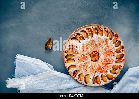 Apple plum cake guarnita con fette di mela e susina fotografato su uno sfondo scuro. Foto Stock