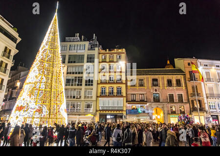 La folla di gente che passeggia nei pressi del albero di Natale decorato su Plaza de la Constitucion nel centro di Malaga, Spagna Foto Stock