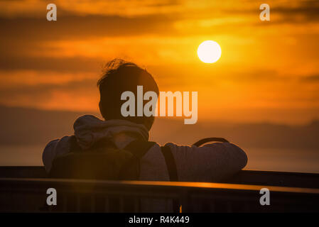 Vista posteriore del viaggiatore uomo che guarda il mare al tramonto a Shizuoka, Giappone. Foto Stock