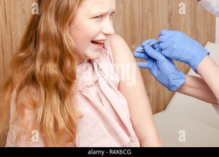 Close-up shot di pediatra dando una iniezione intramuscolare di un vaccino per una ragazza preteen braccio del bambino - Concetto di vaccinazione Foto Stock