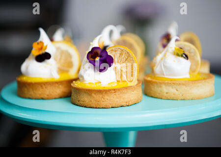 Poco gustosi tortini cremosa con fettina di limone e crema bianca servita su piastra in un ristorante italiano. Deliziosa piccola pasticceria per dessert in Bakery Cafe Foto Stock