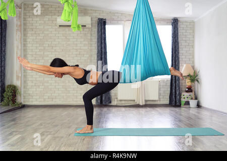 Lunghezza completa di montare la giovane donna facendo antigravity esercizi yoga in studio Foto Stock