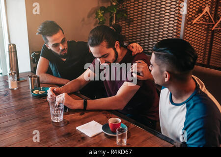 A sostegno di giovani uomini di incoraggiare i loro cuori affranti amico. Arabian ragazzi allietare lui e consigliare nel ristorante. Il concetto di amicizia. Foto Stock