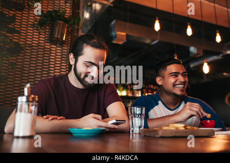 Felice arabian giovani uomini appesi in loft cafe. Due razza mista amici divertendosi nel lounge bar. Ragazzi di refrigerazione e ridere Foto Stock