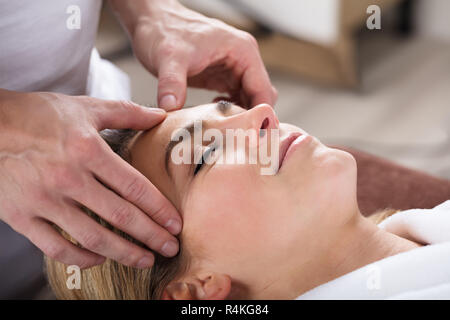 Terapeuta dando massaggio sulla donna di fronte Foto Stock