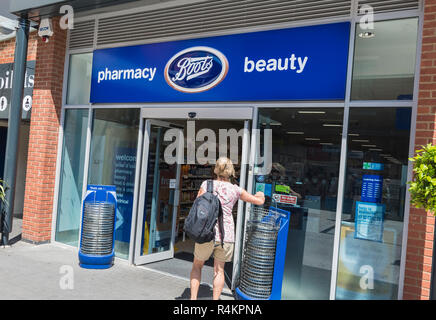 Donna di prelevare carrello mentre si cammina in farmacia stivali & beauty store retail in Gunwharf Quays, Portsmouth, Hampshire, Regno Unito. Foto Stock