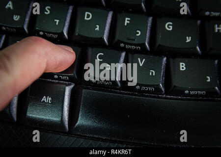 Man digitando su una tastiera con lettere in ebraico e in inglese Foto Stock