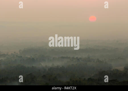 Colorato tramonto sul vulcano Merapi e tempio di Borobudur in misty giungla foresta, Indoneisa Foto Stock