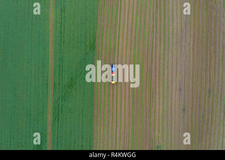 Antenna vista dall'alto di un trattore che lavorano in un'agricoltura arabile campo di coltivazione Foto Stock