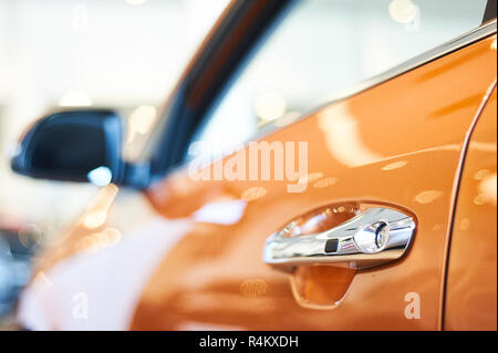 Chrome manico metallico della nuova vettura arancione closeup. auto auto showroom Foto Stock