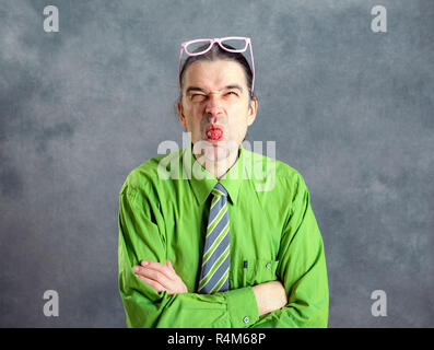 Giovane Uomo in camicia verde,rosa bicchieri e cravatta cercando crazy Foto Stock