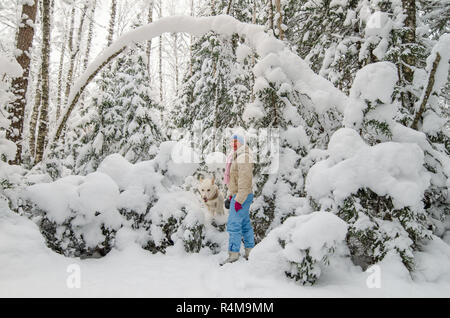 Una donna con un cane in una coperta di neve in inverno forest Foto Stock