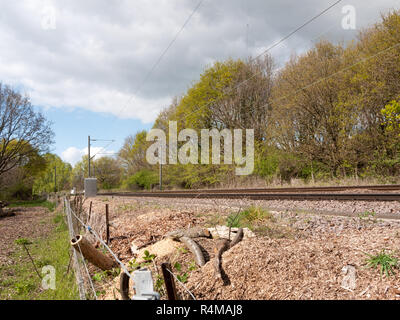 Un binario ferroviario in campagna nel Regno Unito con nessun treno e un recinto di filo spinato e gli alberi in background Foto Stock