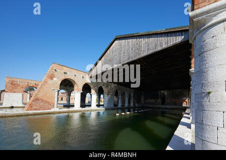 Arsenale veneziano con dock, ampia canal e arcade, cielo blu a Venezia, Italia Foto Stock