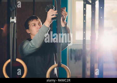 Muscolo-up esercizio athletic uomo facendo un intenso allenamento in palestra su anelli di ginnastica. Foto Stock