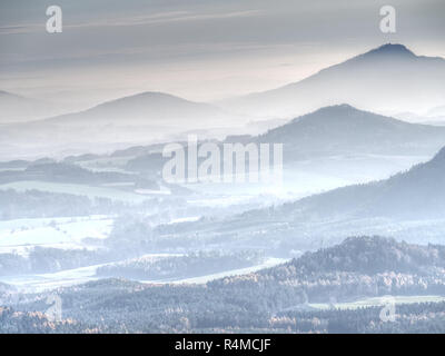 Nebbia blu al di sopra di colline arrotondate nel paesaggio. Profilo del paesaggio reale in mattina luce dorata. Foto Stock