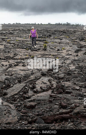 Parco Nazionale dei Vulcani delle Hawaii, Hawaii - un escursionista su un flusso di lava dal vulcano Kilauea. Foto Stock