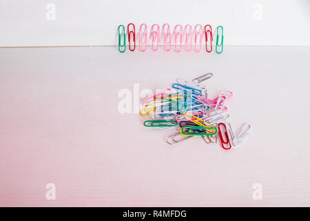Multi colore clip di carta allineate in una fila. Colorati mazzo di clip di carta.Il fuoco selettivo.spazio copia.forniture scolastiche, forniture per ufficio, torna a scuola di arti e mestieri e materiale. Il minimalismo creativo Foto Stock