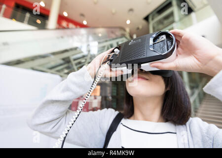 La donna guarda se il dispositivo VR Foto Stock