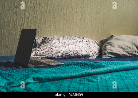 Grigio Laptot posa sul materasso con coperchio color turchese, alcuni cuscini e uno sfondo bianco - per gli studenti di studi, Look Vintage modifica Foto Stock