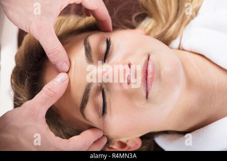 Terapeuta dando massaggio sulla donna di fronte Foto Stock