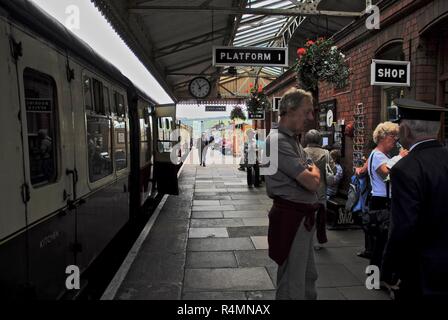 Turisti e il passeggero in piedi sulla piattaforma del Gloucestershire e Warwickshire Steam Railway, REGNO UNITO Foto Stock