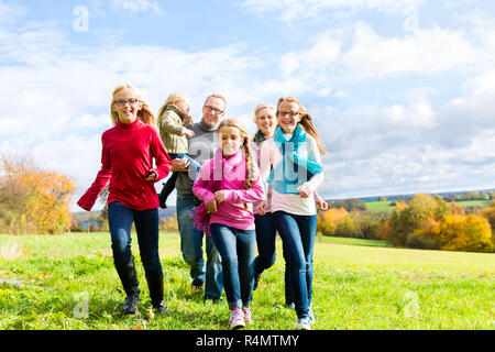 Famiglia in esecuzione attraverso il parco in autunno o in autunno Foto Stock