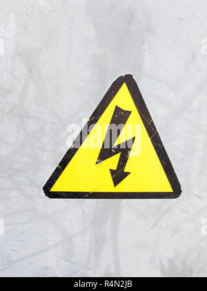 Un simbolo di sicurezza giallo e nero su argento metallico sfondo vite elettrico nel triangolo di avvertenza di sicurezza attenzione Foto Stock