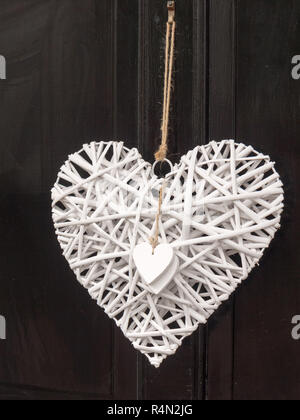 Un moderno e fresco fuori porta decorazione di un amore bianco cuore attaccato e appeso su una porta nera accogliente personale privato Foto Stock