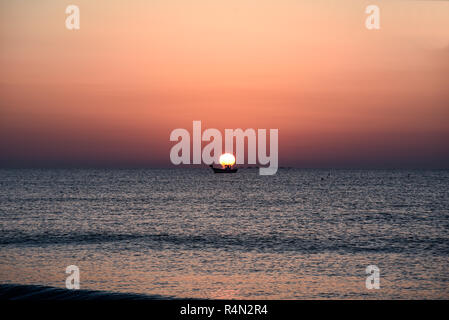 Una barca da pesca fuori presto con sunrise dietro al di sopra del mare Mediterraneo a Guardamar del Segura in Costa Blanca, Spagna. Regione Valenciana Foto Stock