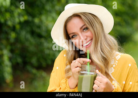 Sorridente giovane donna con i frullati in mason jar Foto Stock