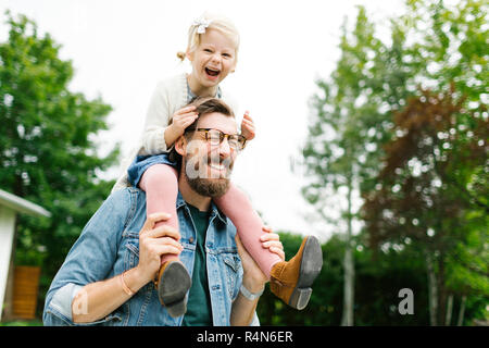 Padre dando figlia piggyback ride Foto Stock
