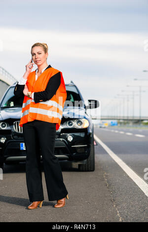 Donna con ripartizione auto chiamando il traino di azienda Foto Stock