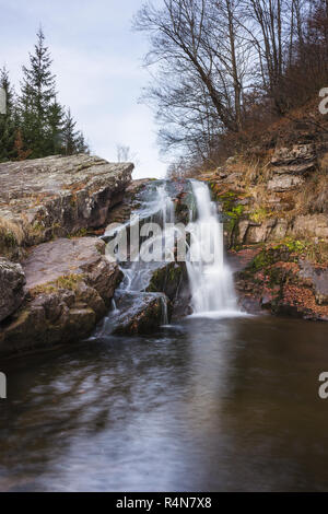 Splendida Mountain Creek Waterfall a cascata verso il basso la parete rocciosa e colori d'autunno foglie rosse Foto Stock