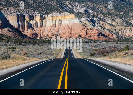 Autostrada della curvatura nella distanza verso scogli colorati in vicino Abiquiu, Nuovo Messico del sud-ovest americano Foto Stock