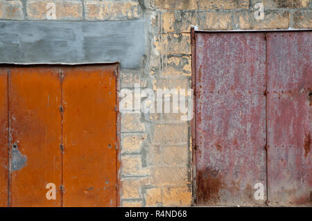 Garage a Gozo, Malta, con rusty in metallo colorato porte impostato in una brezza blocco parete anteriore. Foto Stock