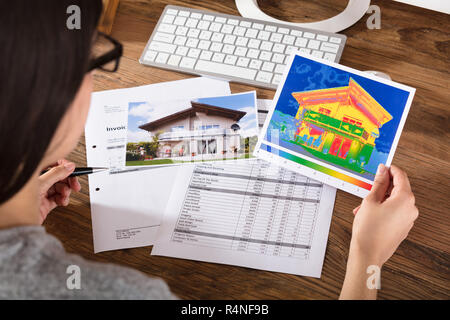 Persona analizzando la perdita di calore di una casa Foto Stock