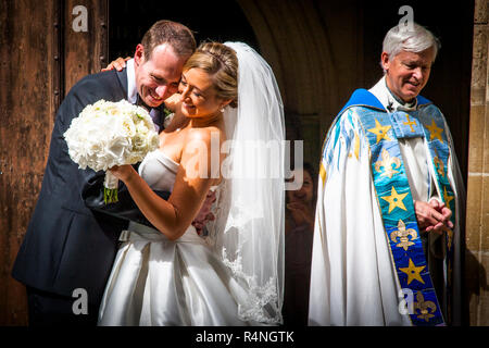 Felicità e soddisfazione. Dopo il matrimonio la coppia e il vicario sorridono Foto Stock