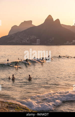 Gruppo di surfisti wave riding in mare al tramonto, Ipanemaâ Beach, Rioâ deâ Janeiro, Brasile Foto Stock