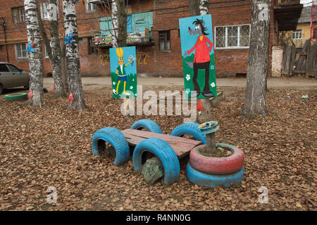 Macchina giocattolo realizzato da rifiuti pneumatici e tronchi di legno sul bambino giochi per bambini in Ivanovo, Russia. Zayats (Lepre) e Volk (lupo), i caratteri delle repubbliche popolari serie animata bene, basta attendere! (Nu Pogodi!) sono raffigurati in background. Attenzione: Questa immagine è una parte di un saggio fotografico di 18 foto con lo stesso campo giochi. Foto Stock