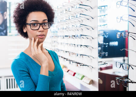 Nero donna cercando sui bicchieri in ottico store Foto Stock