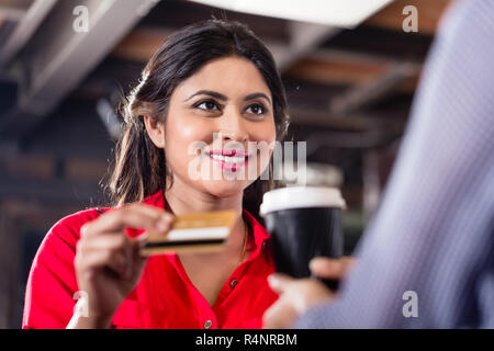 Femmina di pagamento del cliente per un caffè con carta di credito Foto Stock