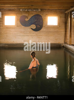 Una donna si imbeve in una piscina di acqua di sorgente calda in un vecchio fienile edificio, Estate Lago, Oregon, Stati Uniti d'America Foto Stock