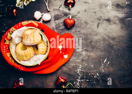 Natale mini bundt cak, all'interno di un contenitore dorato avvolto n una calza di Natale e decorazione su una lavagna nera con zucchero a velo e stampata chri Foto Stock