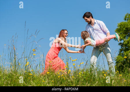 La famiglia sul prato a giocare con la loro figlia piccola Foto Stock