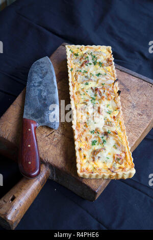 Alsaziana crostata di cipolla con il coltello sul tagliere di legno Foto Stock