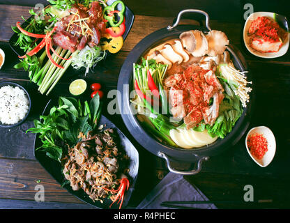 Preparati hot pot di manzo con peperoncino, funghi, erbe, citronella e di riso sul tavolo Foto Stock