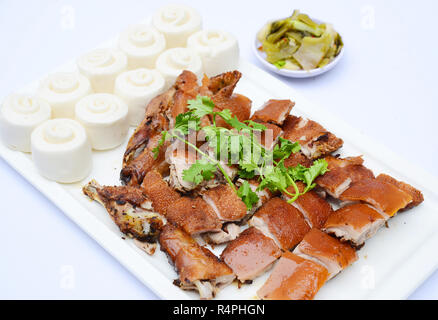 Un trito di grigliate di baby maiale in stile Cinese con gnocchi di patate sul piatto bianco Foto Stock